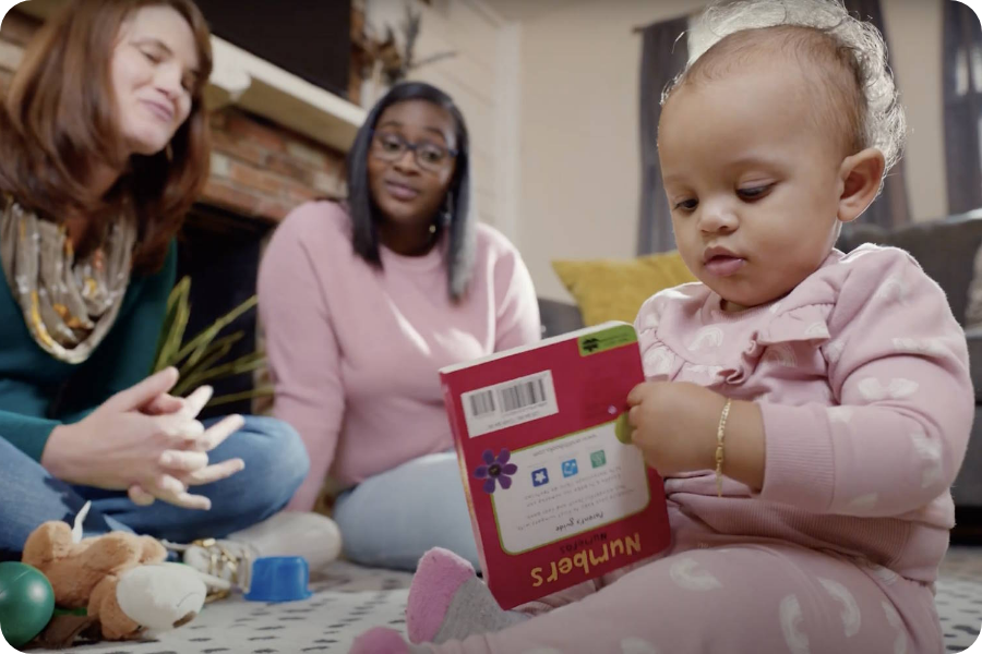 Mother talking with a family support provider and baby with a book